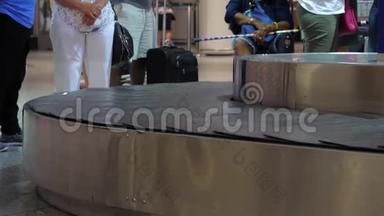 行李传送带上的手提箱在机场的行李认领。 等待行李的人。